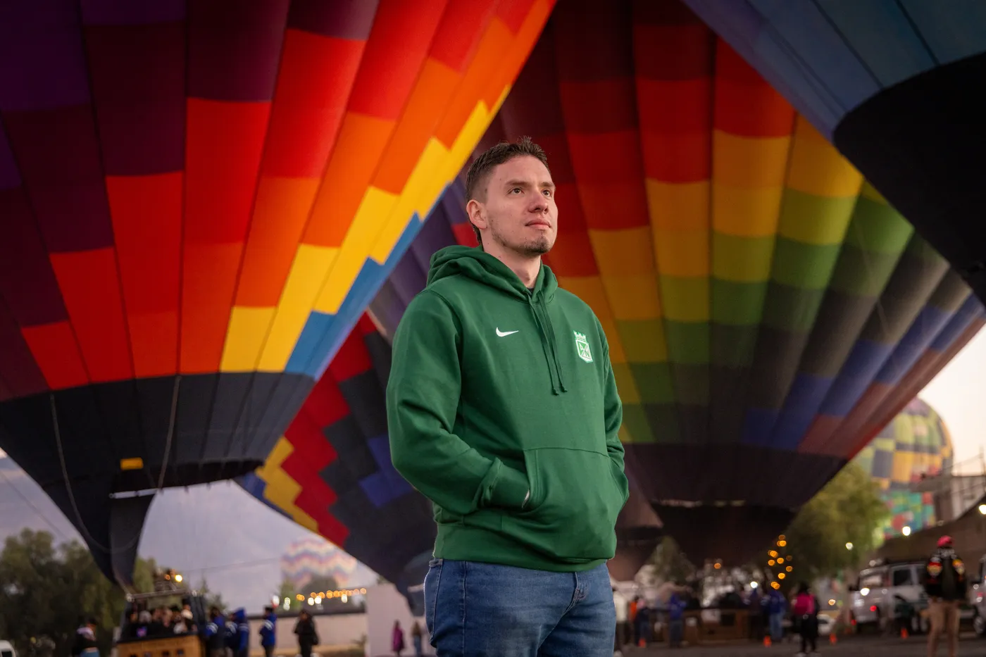 Hombre joven bajo un globo de colores antes del vuelo, entrega de anillo al amanecer